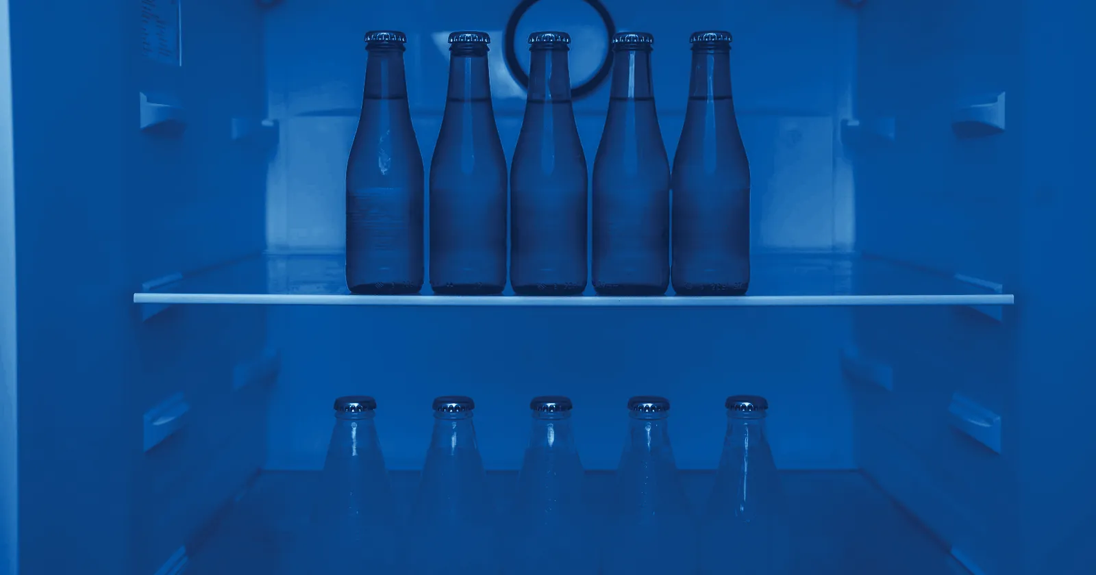 Rows of unlabelled soft drink bottles chilling in a fridge
