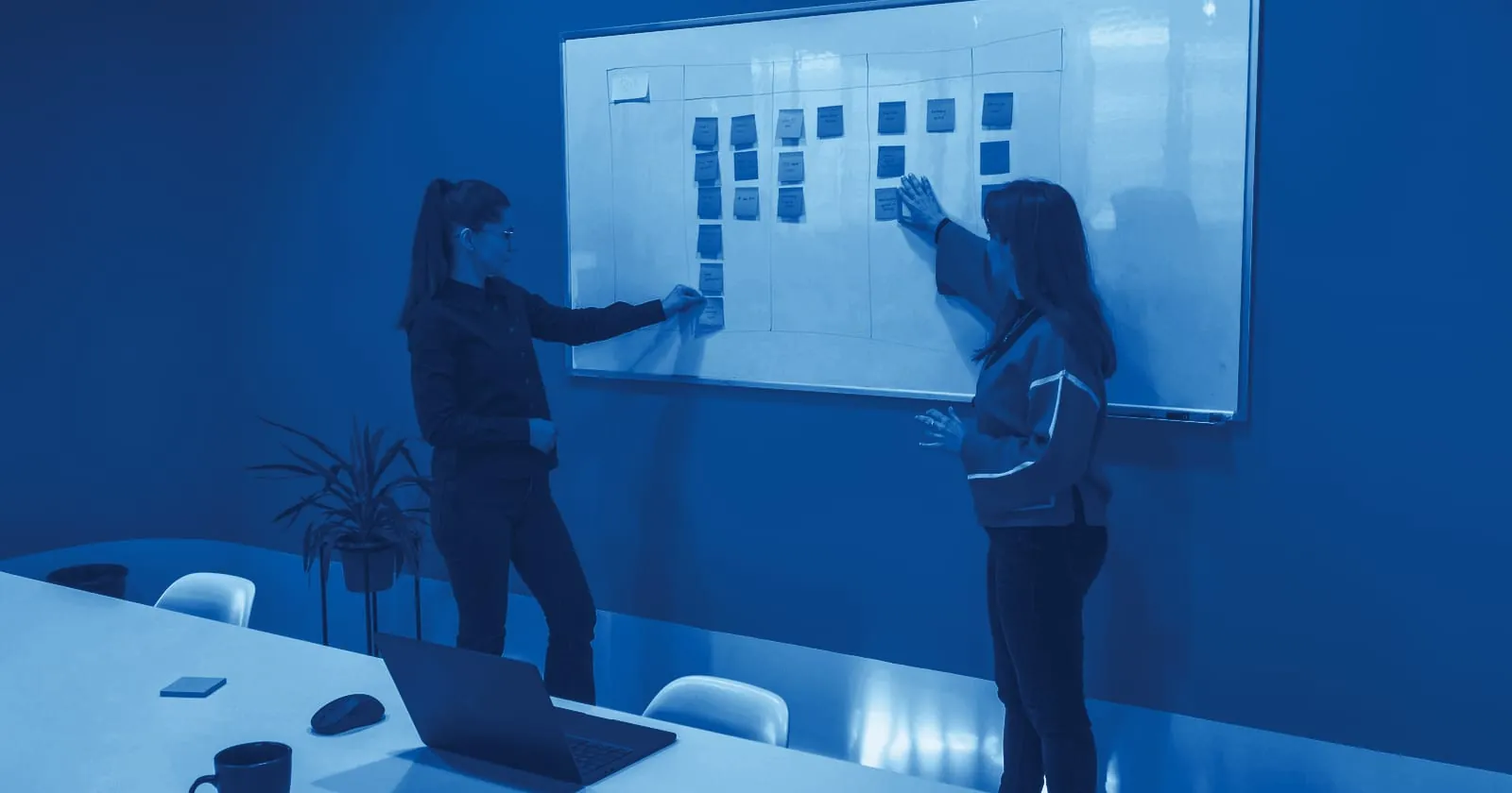Two colleagues planning with sticky notes on a whiteboard