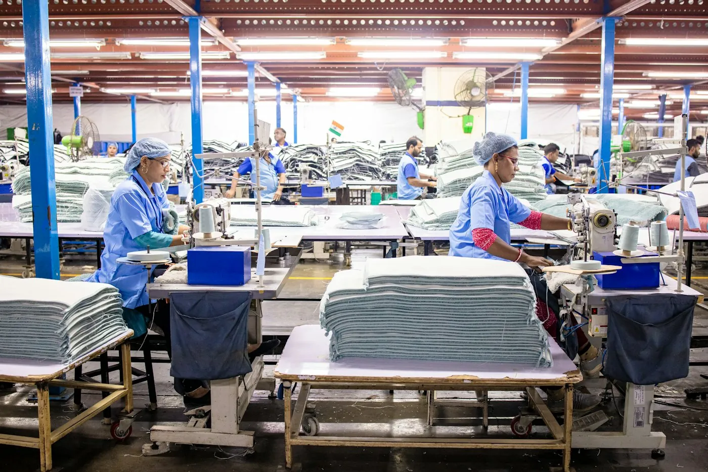 Garment workers sewing on a busy, well-lit factory floor